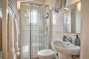 A bathroom with a glass-enclosed shower, a white toilet, and a sink with a mirror above it. - La Terrazza - apartment with breathtaking view (Cortona)