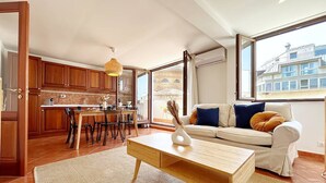 Una sala de estar moderna con un sofá, una mesa de centro y un comedor con armarios de madera y una cocina al fondo.