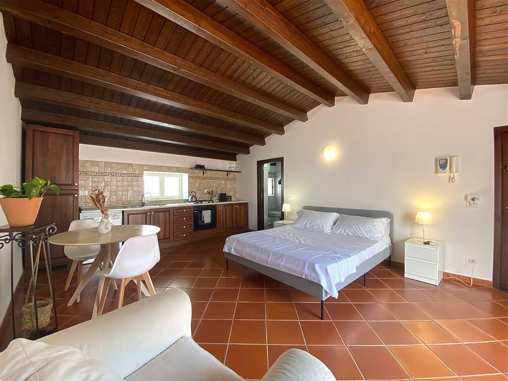 Une chambre à coucher comprenant un lit, une table de chevet et une petite table avec des chaises, située dans l’espace adjacent qui sert de salle à manger.