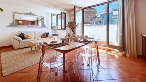Una sala de estar moderna con comedor, ventanas amplias y vistas a edificios.
