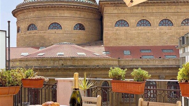 Una mesa dispuesta con comida y bebidas en una terraza con vistas a un edificio histórico.