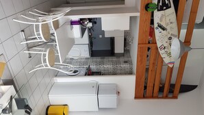 A kitchen with white cabinets, a microwave, a coffee machine, and a yellow trash bin. - T1 bis Mezzanine, Très Lumineux, Proche Plage et Commodités (Le Château-d'Olonne)