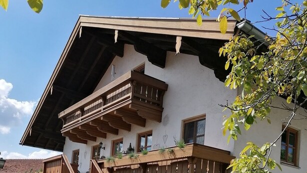 A two-story building with wooden balconies, a staircase, and cobblestone paving. - Ferienwohnung für 2-4 Personen, 1 Sep. Schlafzimmer und Balkon in Chieming-laimgrub (Chieming)