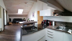 A modern kitchen with a central island, a built-in sink, and wooden flooring. - Ferienwohnung für 2-4 Personen, 1 Sep. Schlafzimmer und Balkon in Chieming-laimgrub (Chieming)