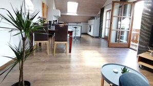 A modern kitchen with wooden cabinets, a dining area with a table and chairs, and a large window providing natural light. - Ferienwohnung für 2-4 Personen, 1 Sep. Schlafzimmer und Balkon in Chieming-laimgrub (Chieming)