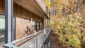 Une cabane en bois dotée d’un balcon donnant sur un paysage rocheux et les couleurs automnales des arbres.
