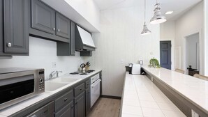 Une cuisine moderne avec des meubles gris, un four à micro-ondes encastré, une cuisinière et un grand îlot central doté d’un évier.