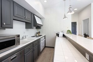 Une cuisine moderne avec des meubles gris, un four encastré et un plan de travail blanc.