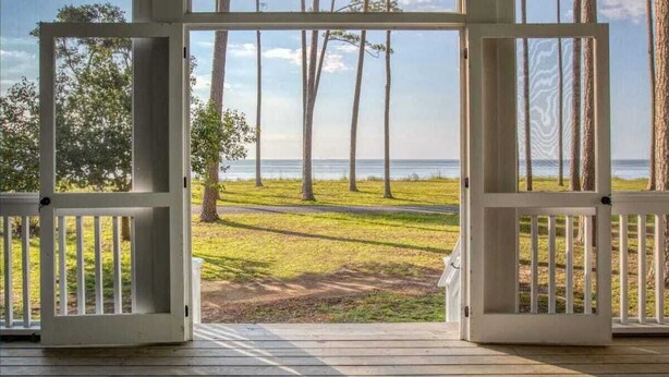 Una terraza de madera con vistas al océano y a los árboles.