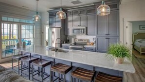 Una cocina moderna con una isla grande, taburetes de bar e iluminación colgante.