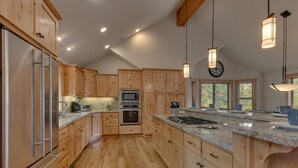 Une cuisine spacieuse dotée de meubles en bois, d’appareils électroménagers en acier inoxydable et d’un grand îlot central avec une plaque de cuisson intégrée.