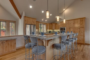 Una cocina moderna con armarios de madera, una isla central con taburetes altos e iluminación colgante.
