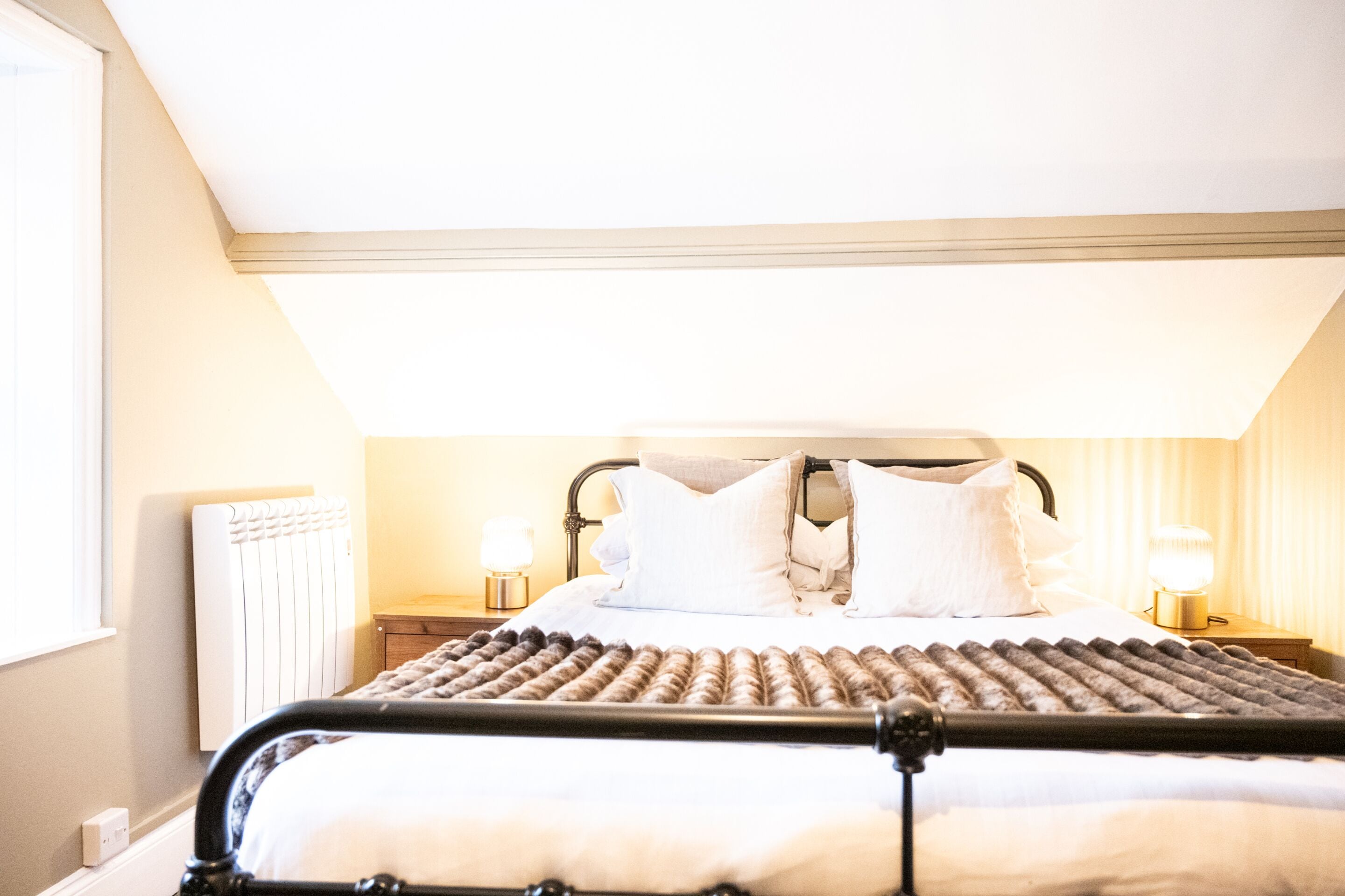 A bed with a metal frame, white bedding, and two bedside lamps.
