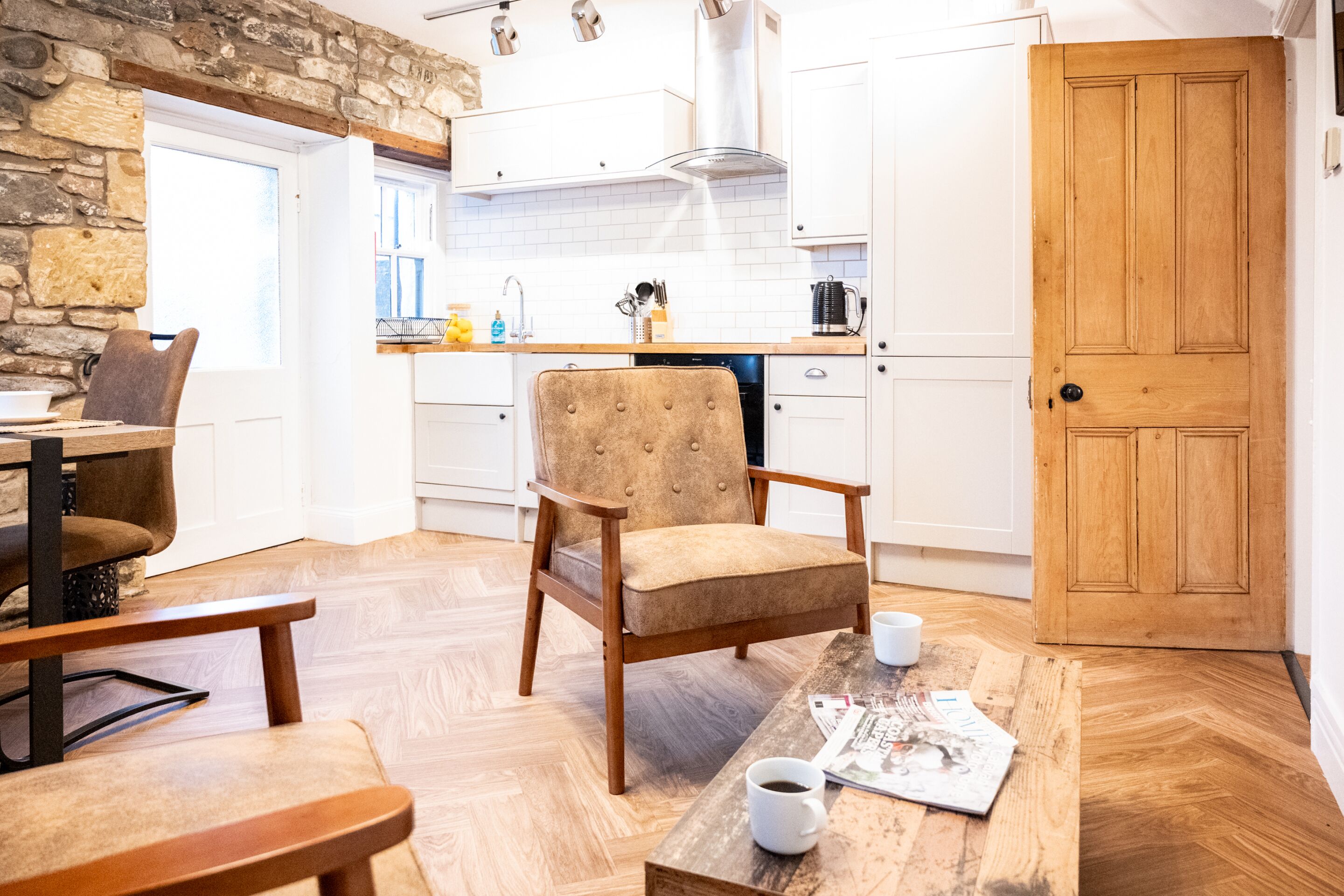 Una cocina acogedora con pared de piedra, muebles de madera y una puerta de madera.