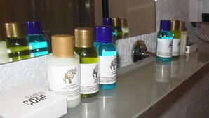 Uma bancada de banheiro com espelho, uma caixa de sabonete e várias embalagens de condicionador de cabelo.