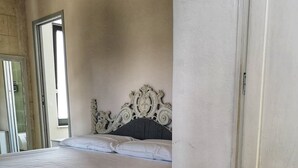 A bedroom with a bed, a white headboard, and a door. - Relais Grottone (Ostuni)