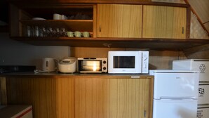 Eine kleine Küche mit Holzausstattung, einem Toaster, einer Mikrowelle und einem Kühlschrank.
