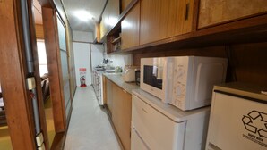 Eine schmale Küche mit Holzausstattung, einer Mikrowelle, einem Kühlschrank und einem Spülbecken.