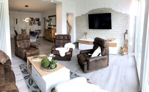 A modern living room with leather sofas, a white console table, and a stone accent wall.