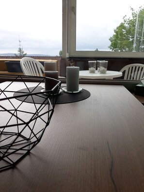 Ein Holztisch mit einer geometrischen Metallskulptur, einer Kerze und einem Glasbehälter mit weißen Gegenständen.