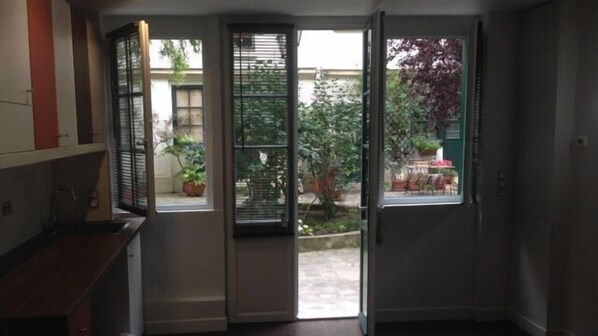 A room with a sliding door leading to an outdoor area with potted plants and a small table.