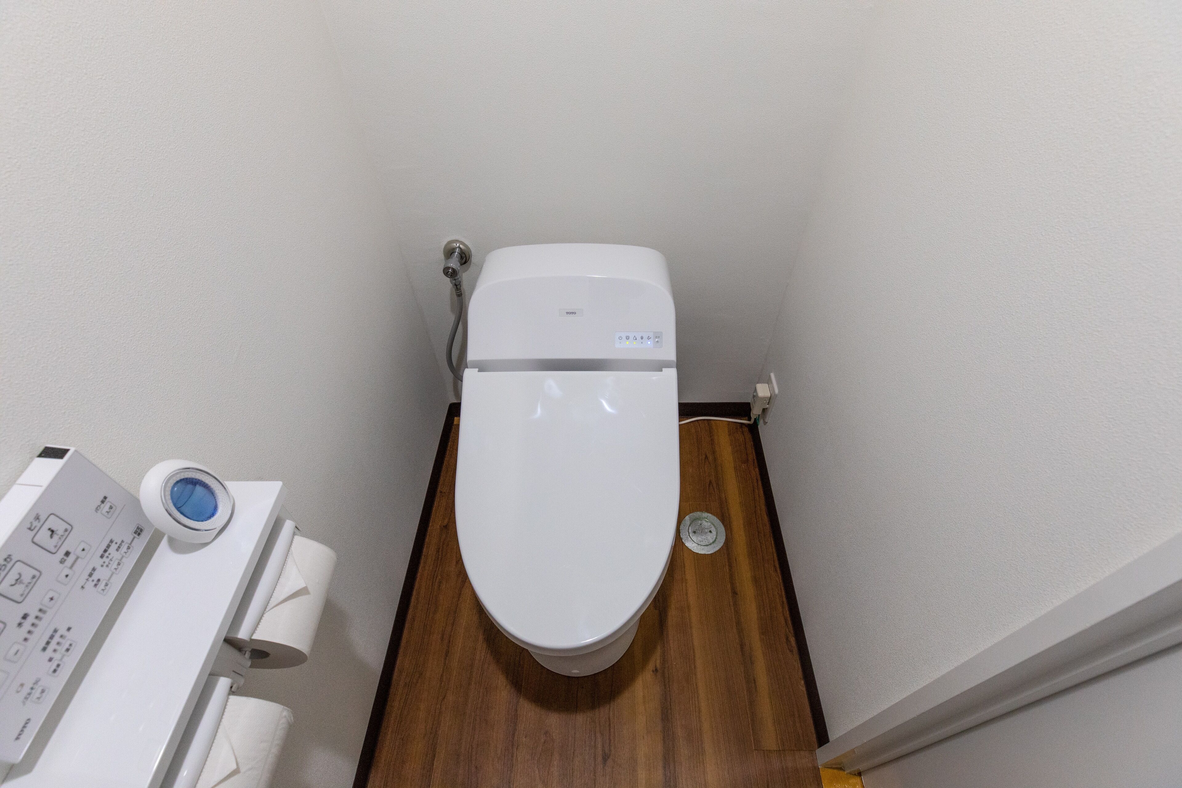 A toilet with a control panel and a bidet attachment.