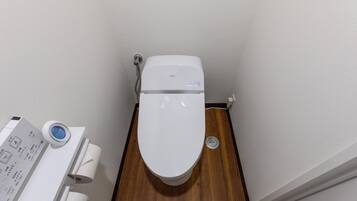 A toilet with a control panel and a bidet attachment.