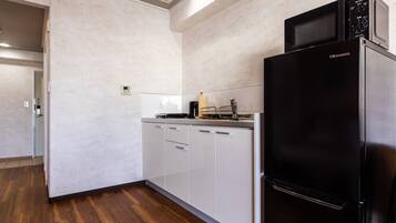 A modern kitchen with white cabinetry, a black refrigerator, and a microwave on top.