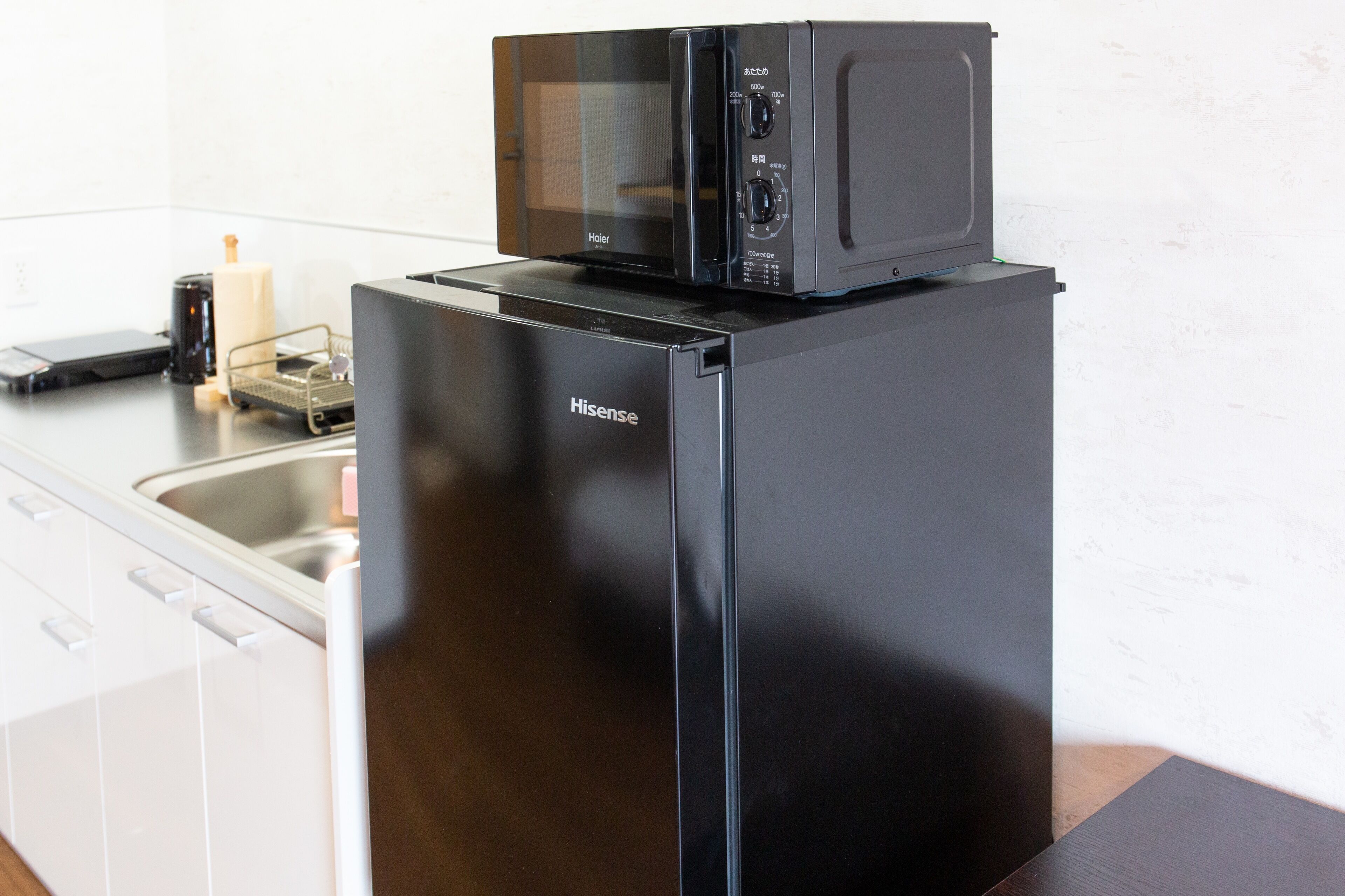 Une cuisine avec un réfrigérateur noir et un four à micro-ondes placé sur le dessus.