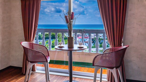 Un balcon avec une table et deux chaises, offrant une vue sur la côte.