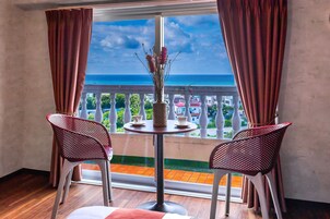 Un balcón con mesa y dos sillas, con vista al mar.