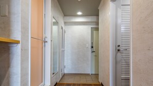 Un couloir étroit doté d’un plancher en bois, de murs blancs et d’une porte à panneaux ajourés.