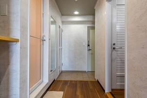 Un pasillo estrecho con suelo de madera, paredes blancas y una puerta con diseño persiana.