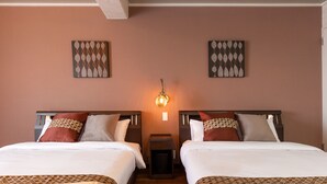 Une chambre d’hôtel avec deux lits, une table de chevet et un luminaire fixé au mur.