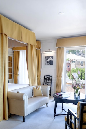 A room with a sofa, a table, and a chair. There is a window with curtains.