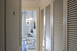 A hallway with a glass table, chairs, and a potted plant.