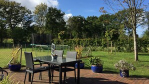 An outdoor patio with a table and chairs, surrounded by potted plants and a grassy area. - A little oasis in the middle of nature (Friedeburg)