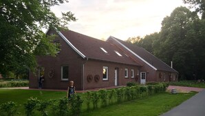 A brick building with a sloped roof and a small porch. - A little oasis in the middle of nature (Friedeburg)