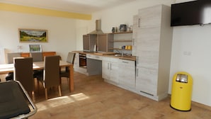 A modern kitchen with a dining area, a built-in oven, and a TV mounted on the wall. - A little oasis in the middle of nature (Friedeburg)