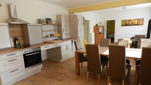 A modern kitchen with a central island, built-in oven, and a dining area with a table and chairs. - A little oasis in the middle of nature (Friedeburg)