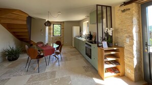 Eine moderne Küche mit Steinwand, eine Essecke mit rotem Tisch und eine Treppe.