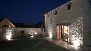 Ein Steinhaus mit gut beleuchtetem Eingang und einer kleinen Terrasse.