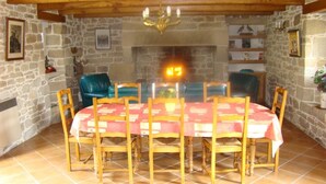 A dining area with a round table covered with a red tablecloth, surrounded by wooden chairs.