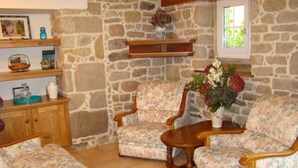 Uma sala de estar aconchegante com mobiliário estampado com flores, uma parede de pedra e uma janela com vista.