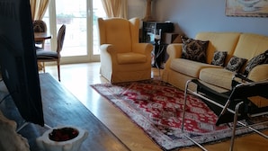 Un salon avec un canapé, un fauteuil et un téléviseur posé sur une table en bois.