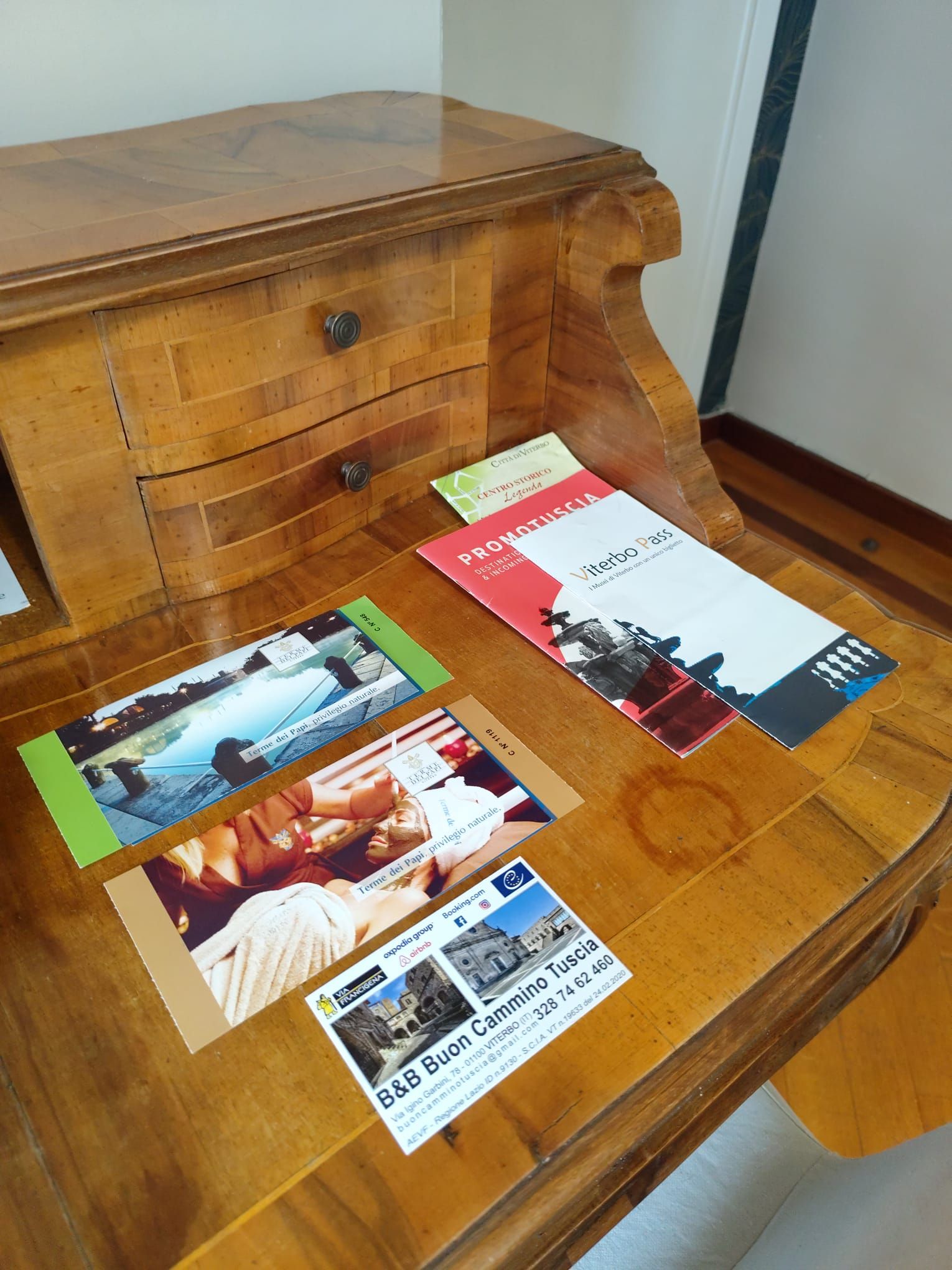 A wooden table with brochures and a business card.
