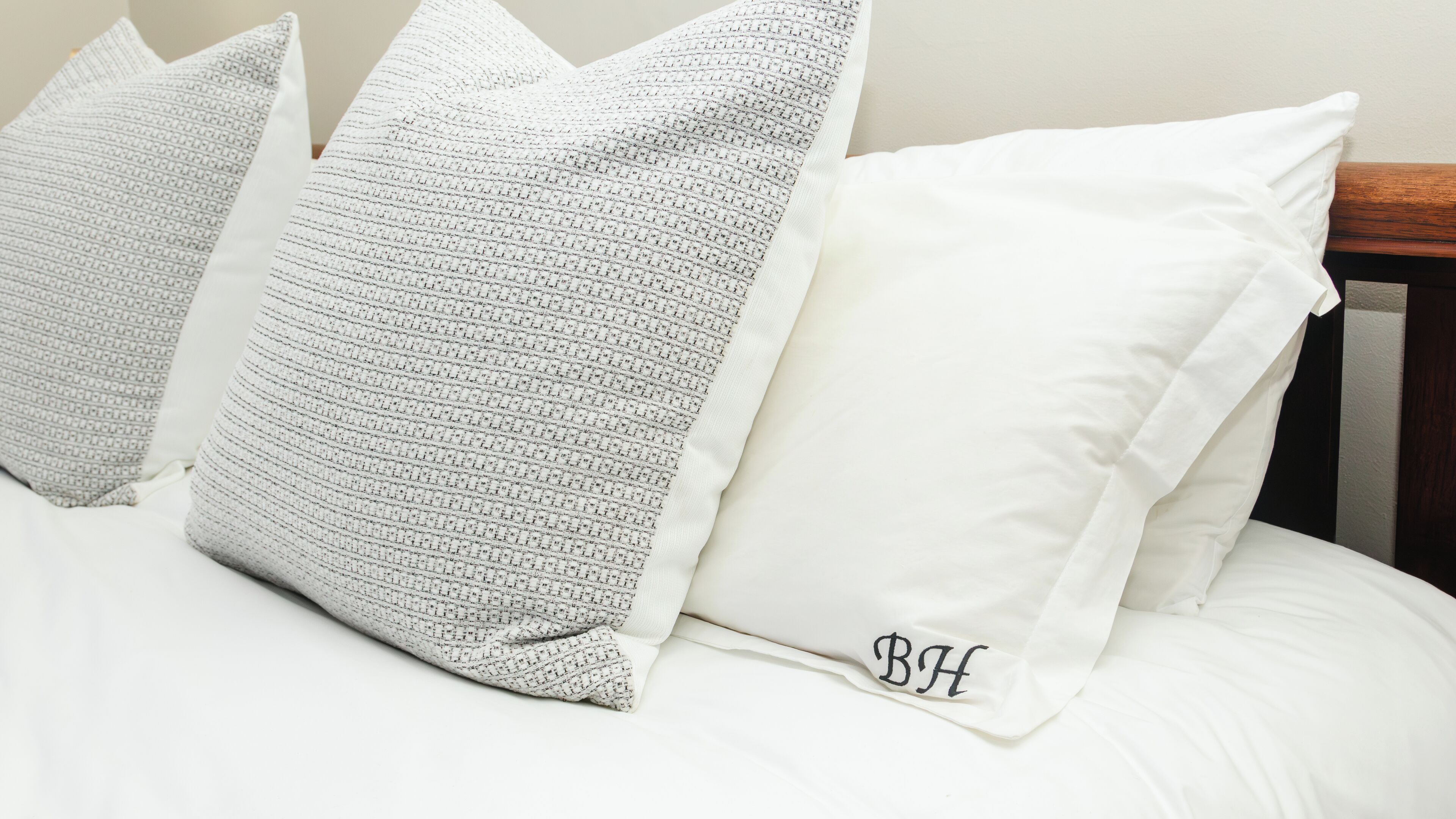 Un letto con tre cuscini, uno con un monogramma.