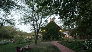 A garden with a brick pathway, a wooden deck, and a red Adirondack chair.