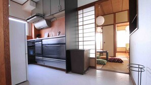 A modern kitchen with stainless steel appliances, a dining area with tatami mats, and a traditional sliding door. - Goraku Shinfukae (Osaka)