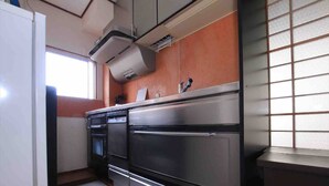 A kitchen with stainless steel appliances, a window, and a view of the outside. - Goraku Shinfukae (Osaka)
